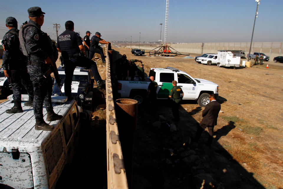 <p>Mexican federal police officers (L) look over the current border fence, while U.S. border patrol authorities visit the site where several prototypes for U.S. President Donald Trump’s border wall with Mexico have been built, in this picture taken from the Mexican side of the border, in Tijuana, Mexico, Oct. 26, 2017. (Photo: Jorge Duenes/Reuters) </p>