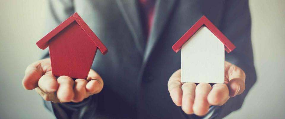 Businessman holding two houses and can not decide choosing the right house