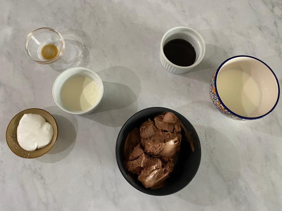 Flat lay of chocolate ice cream, chocolate syrup, cream, and marshmallow fluff.