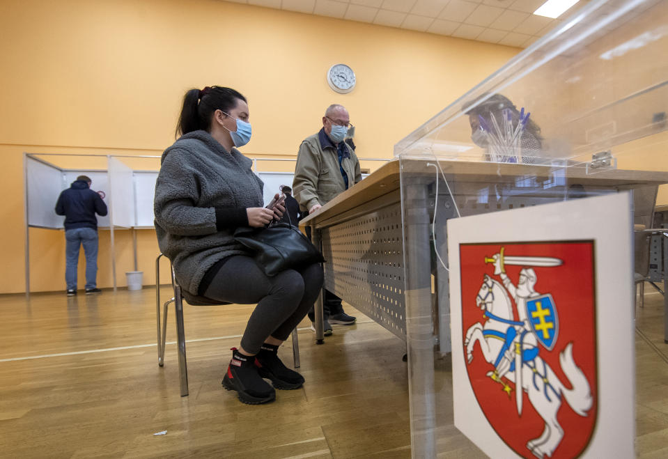 Lithuanian's, wearing face masks to protect against coronavirus, wait for ballots at a polling station during early voting in the second round of a parliamentary election in Vilnius, Lithuania, Thursday, Oct. 22, 2020. Lithuanians will vote in the second round of a parliamentary election on upcoming Sunday during the rise in the incidence of coronavirus infection in the country. (AP Photo / Mindaugas Kulbis)