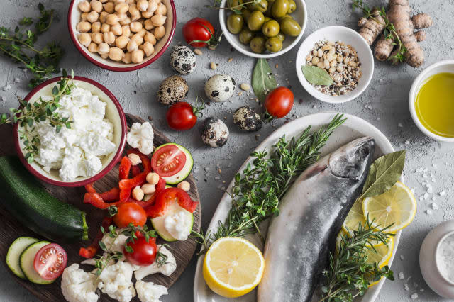 Mediterranean style food background. Fish, vegetables, herbs, chickpeas, olives, cheese on grey background, top view. Healthy food concept. Flat lay