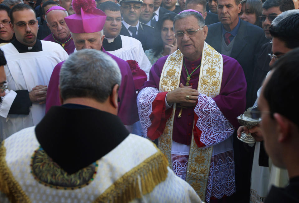 Latin Patriarch of Jerusalem Fouad Twal, center, arrives to the Church of the Nativity, traditionally believed by Christians to be the birthplace of Jesus Christ on the Christmas Eve in the West Bank town of Bethlehem, Tuesday, Dec. 24, 2013. (AP Photo/Majdi Mohammed)