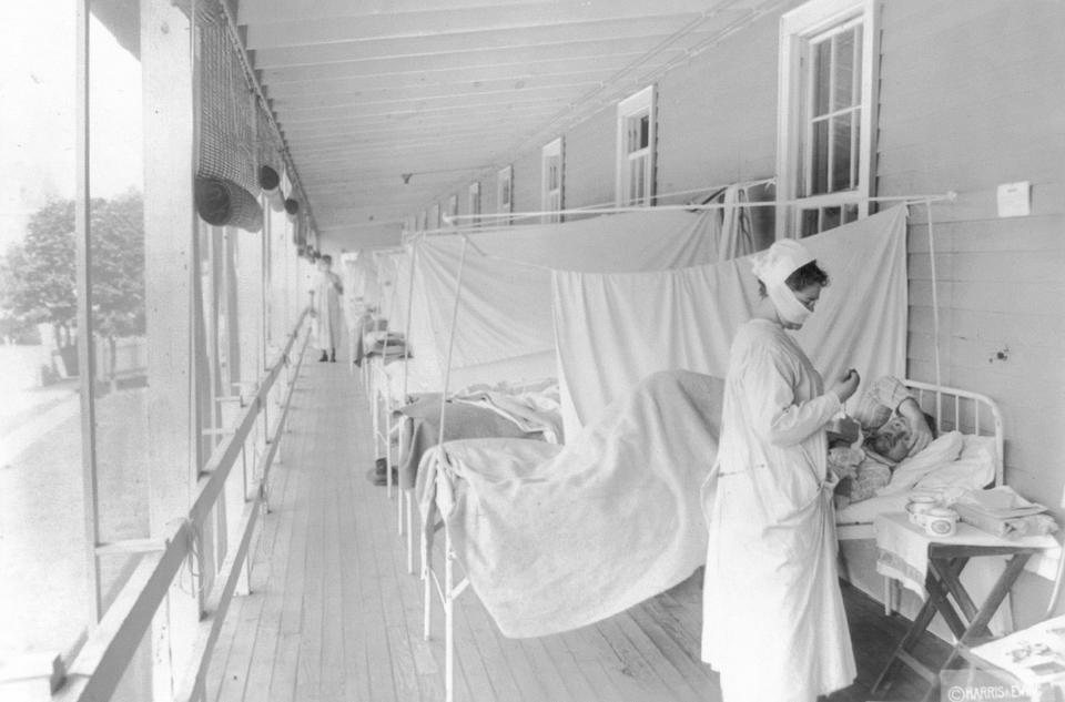 FILE - In this November 1918 photo made available by the Library of Congress, a nurse takes the pulse of a patient in the influenza ward of the Walter Reed hospital in Washington. Science has ticked off some major accomplishments over the last century. The world learned about viruses, cured various diseases, made effective vaccines, developed instant communications and created elaborate public-health networks. Yet in many ways, 2020 is looking like 1918, the year the great influenza pandemic raged. (Harris & Ewing/Library of Congress via AP, File)