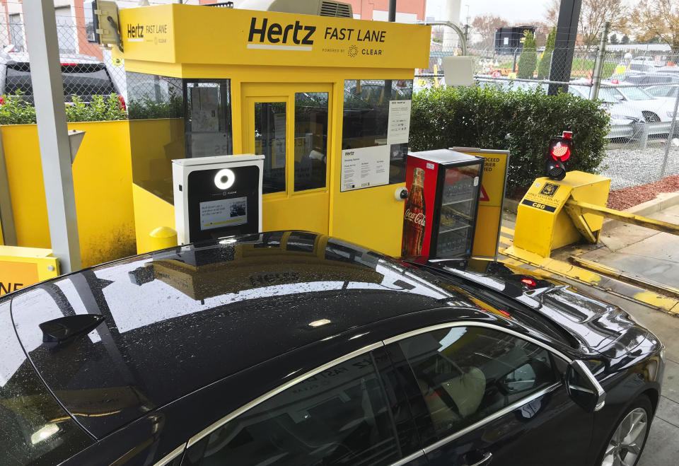 In this Friday, Dec. 7, 2018, photo, a rental car approaches a biometric scanning machine at the exit of the Hertz facility at Hartsfield-Jackson Atlanta International Airport, in Atlanta. In a first for the rental car industry, Hertz is teaming up with Clear, the maker of biometric screening kiosks found at many airports and stadiums. Hertz says the partnership will slash the time it takes to pick up a rental car. (AP Photo/Jeff Martin)