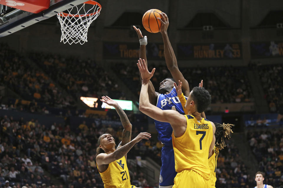 BYU forward Atiki Ally Atiki, top, is defended by West Virginia center Jesse Edwards (7) and guard RaeQuan Battle (21) during the first half of an NCAA college basketball game Saturday, Feb. 3, 2024, in Morgantown, W.Va. (AP Photo/Kathleen Batten)