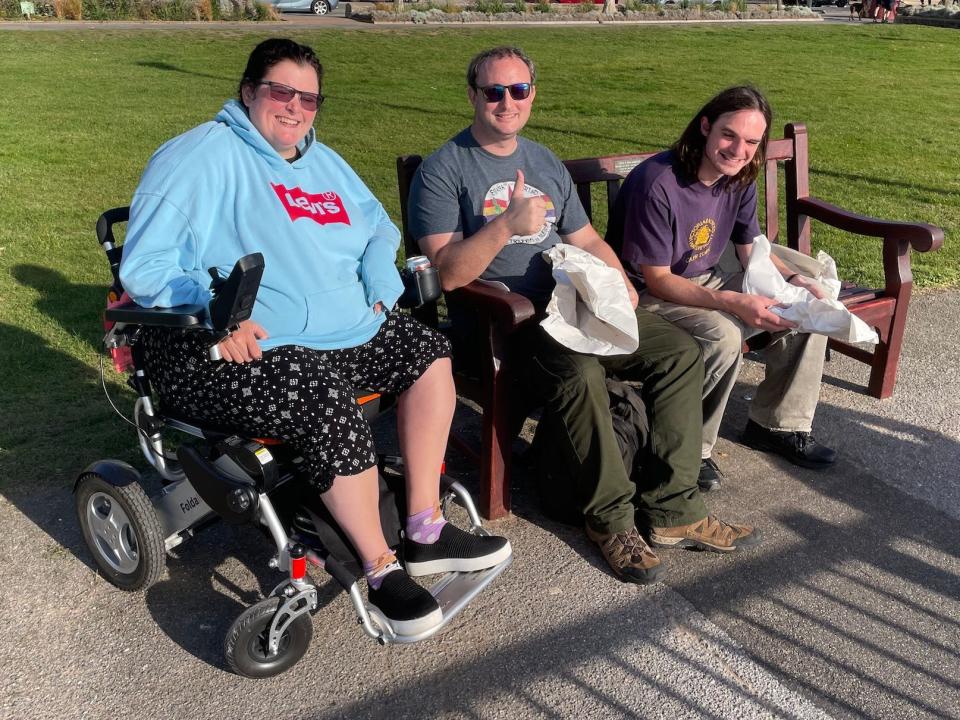 Simpson in a wheelchair sitting in a park with friends, smiling