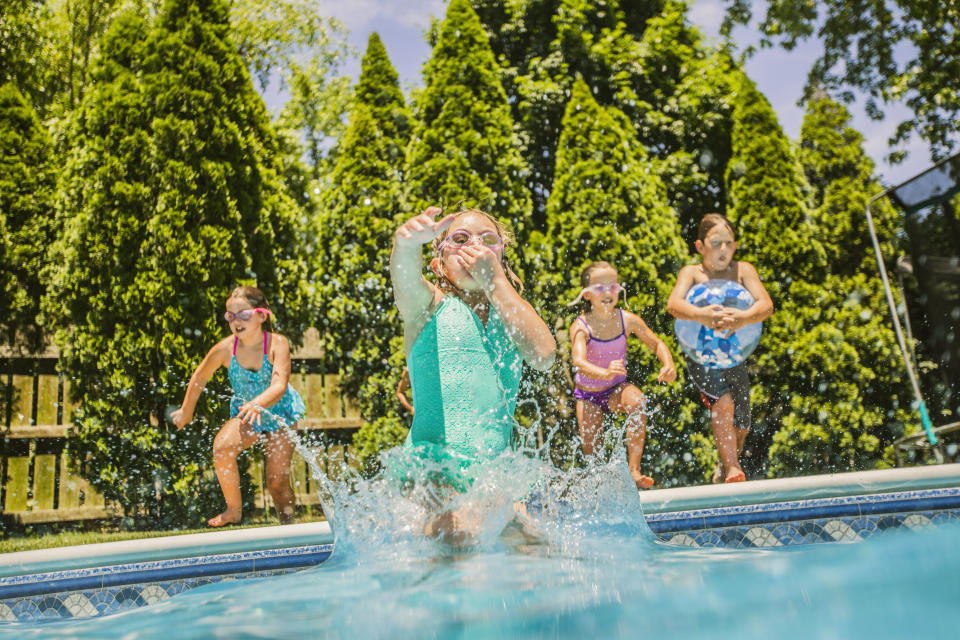 Little girls jump into a pool at a pool party. 