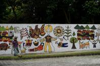 A gardener works in front of a mural honoring Oscar Romero, at the entrance of the Divina Providencia parish in San Salvador, on October 11, 2018 -- days before he is due to be canonized by Pope Francis