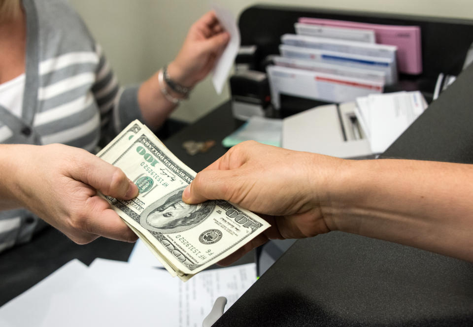 woman's hands get cash from a bank clerk