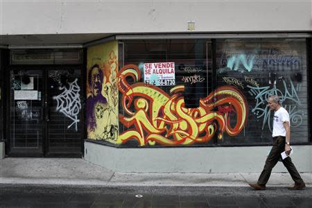 A pedestrian passes a closed shop with a for sale sign outside, along Paseo de Diego in San Juan's Rio Piedras district, September 3, 2013. REUTERS/Alvin Baez