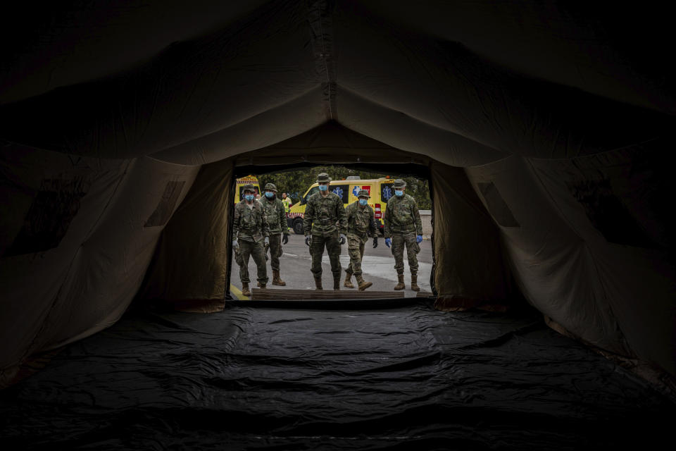 Spanish Army soldiers mount a tent to be used by hospital patients during the coronavirus outbreak in Madrid, Spain, Monday, March 30, 2020. Bells tolled in Madrid's deserted central square and flags were lowered in a day of mourning Monday as Spain raced to build field hospitals to treat an onslaught of coronavirus patients. The new coronavirus causes mild or moderate symptoms for most people, but for some, especially older adults and people with existing health problems, it can cause more severe illness or death. (AP Photo/Bernat Armangue)