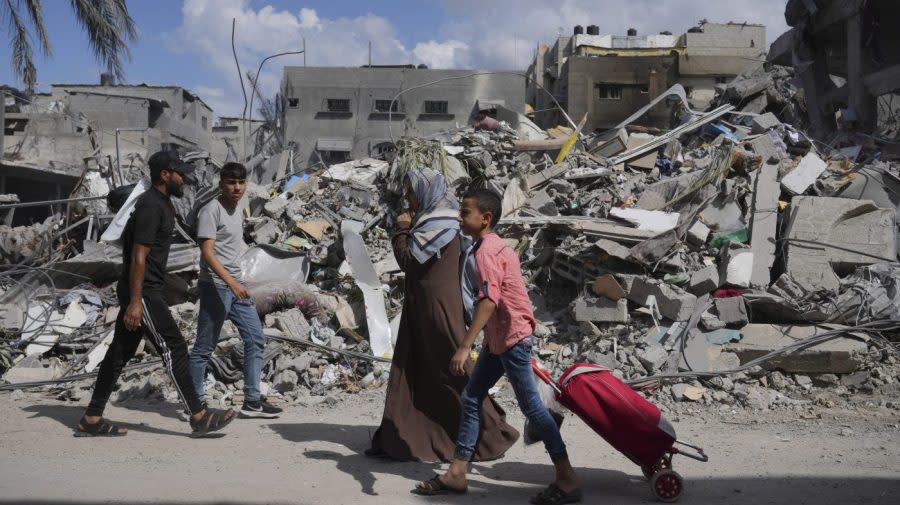 Palestinians by the buildings destroyed in Israeli airstrikes in Bureij refugee camp, Gaza Strip, Wednesday, Oct. 18, 2023. (AP Photo/Hatem Moussa)