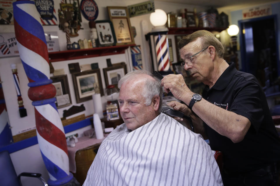 Stan Morin gives a haircut to Jeff McGee at his barber shop, Thursday, May 21, 2020, in Plainville, Kan. Morin said he has been two to three times busier than normal after reopening a week earlier following a 2-month closure in an effort to stem the spread of the coronavirus. (AP Photo/Charlie Riedel)