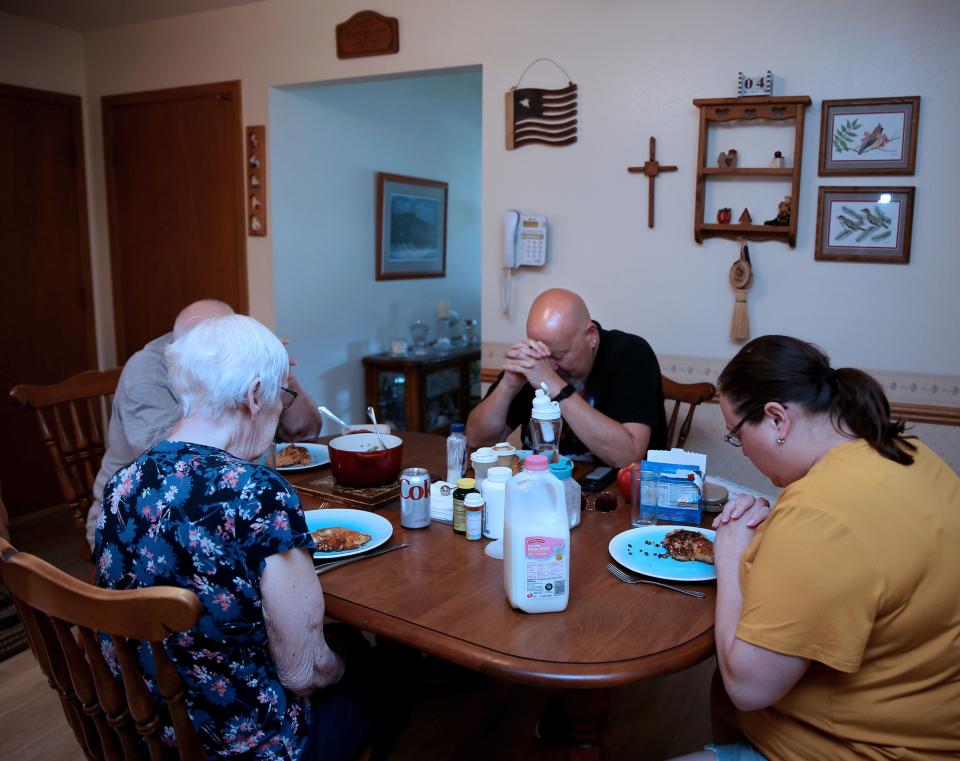 Jim Garvey, center in black shirt, prays with his family, sister Erin, right, mother, Lynn, back to camera, and father, Dennis, far left, before their family meal, in Kewaskum. Garvey prepared green beans, panko covered tilapia and brown rice quinoa.