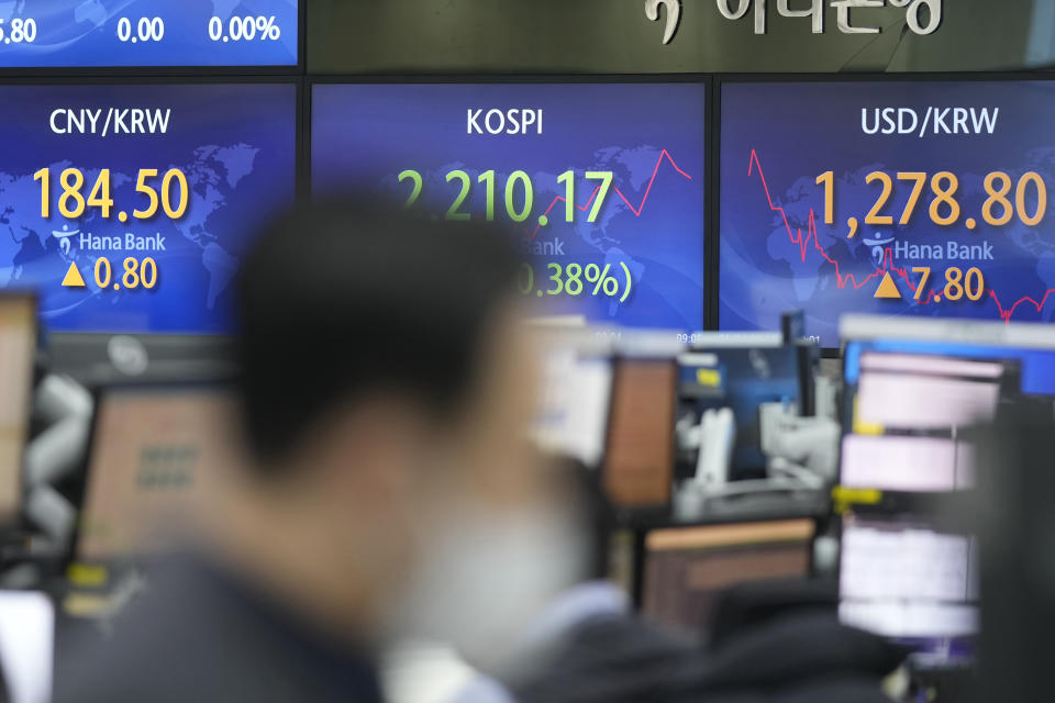 A currency trader walks by the screens showing the Korea Composite Stock Price Index (KOSPI), center, and the foreign exchange rates at a foreign exchange dealing room in Seoul, South Korea, Wednesday, Jan. 4, 2023. Asian stock markets rose Wednesday ahead of the release of minutes from a Federal Reserve meeting that investors hope might show the U.S. central bank is moderating its plans for more interest rate hikes to cool inflation. (AP Photo/Lee Jin-man)