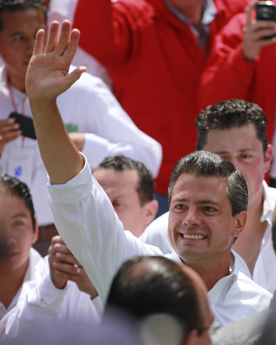 Revolutionary Institutional Party (PRI) presidential candidate, Enrique Pena Nieto, right, waves to the crowds as he arrives for a massive rally at the Azteca stadium in Mexico City, Mexico, Sunday, June 24, 2012. Next July 1, Mexico will hold presidential elections. (AP Photo/Dario Lopez-Mills)