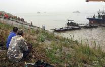 Chinese villagers watch as rescue teams head out to search for survivors of a passenger ship carrying more than 450 people which sunk in the Yangtze river, off Jianli, in China's Hubei province, on June 2, 2015