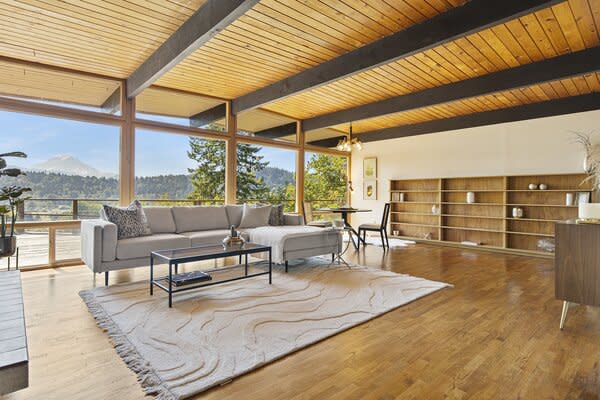 The living area features wood-paneled ceilings, a large brick fireplace, post-and-beam construction, and floor-to-ceiling glazing.