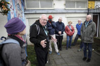 In this Tuesday, Oct. 15, 2019 photo former IRA member Jack Duffin, from Belfast Political Tours talks to tourists in west Belfast, Northern Ireland. (AP Photo/Peter Morrison)