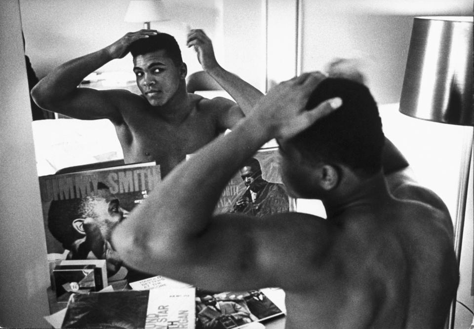 The boxing heavyweight contender then known as Cassius Clay combs his hair in the mirror in a Pittsburgh hotel room on Jan. 24, 1963. (Photo: Marvin Lichtner/The LIFE Images Collection via Getty Images/Getty Images)