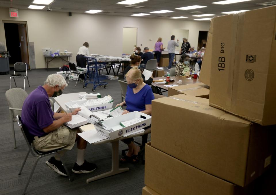 Denis Strauch and Elaine Edmonds who have been volunteering at 3 elections for Denis and 9 for Elaine process absentee ballots before they are scanned and processed at a building at the Livonia City Hall complex in Livonia, Michigan on Tuesday, August 4, 2020.