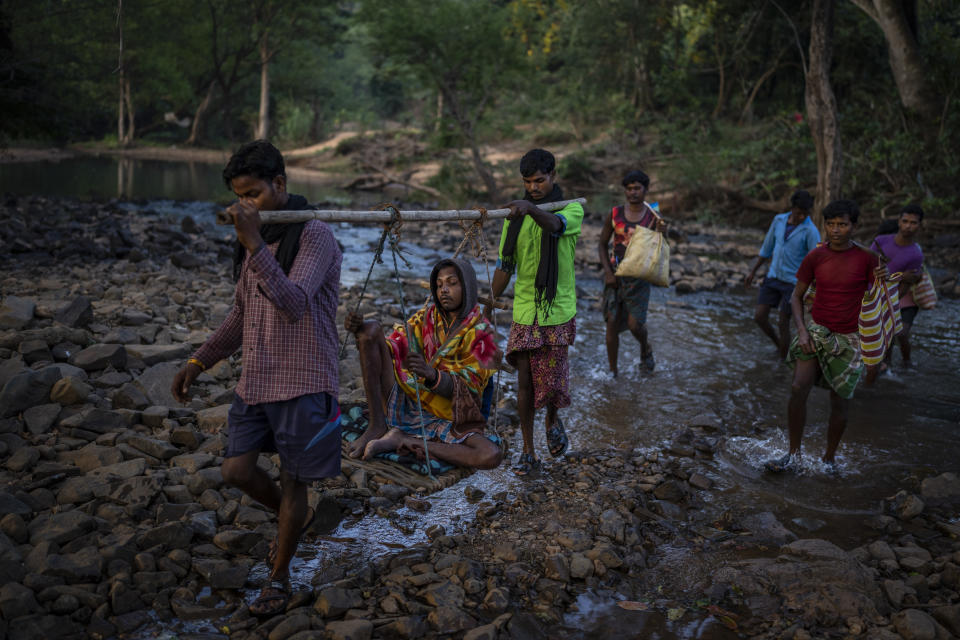 Villagers, carrying a sick man in a makeshift palanquin, cross a stream through Abhujmarh, or "the unknown hills," on their way to a nearest health center, some 20 kilometers away near Orchha in central India's Chhattisgarh state, Nov. 15, 2022. Motorbike ambulances are helping pregnant women and very sick patients to reach hospitals in Naryanpur district, in central India's Chhattisgarh state. Many of the heavily forested district's villages are nearly inaccessible, often miles away from motorable roads and connected only by rough paths spanning over streams and hills. The state's health system has struggled to reach remote villages that can be ten miles or more from roads. The lack of roads often forces villagers to resort to makeshift palanquins to transport the very sick. (AP Photo/Altaf Qadri)