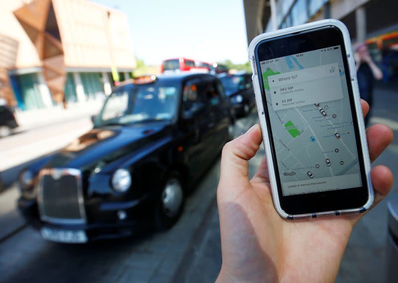 A photo illustration shows the Uber app on the mobile phone and a black cab in London