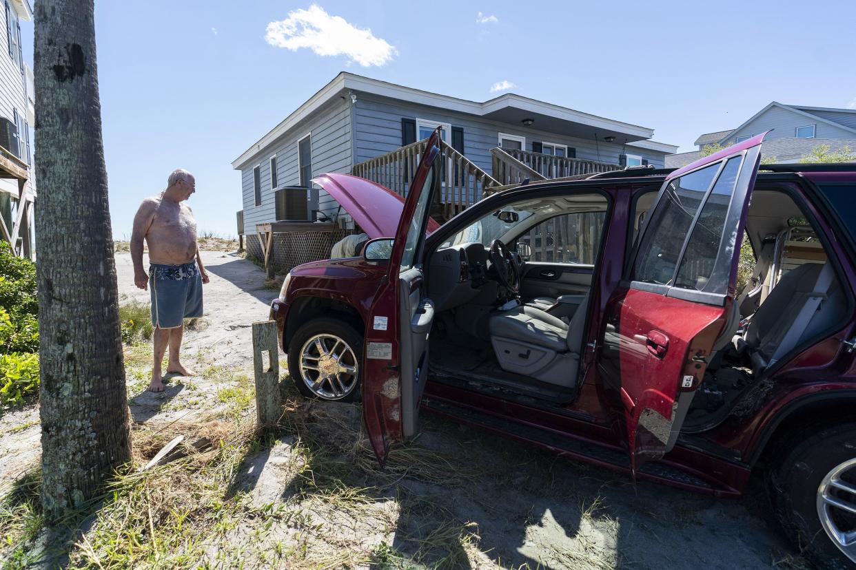 Walter McGee, of Greenville, S.C., looks at his ruined car after the effects of Hurricane Ian, Saturday, Oct. 1, 2022, in Pawleys Island, S.C.