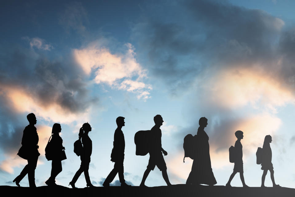 Silhouette of refugees with luggage walking in a row. (Source: Getty)