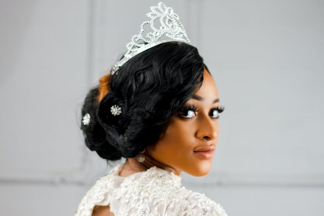 Black woman bride in wedding dress and crown wearing hair in an updo