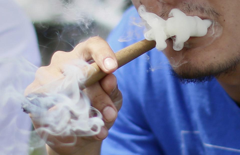 A man smokes a large marijuana blunt at the 4/20 marijuana event in downtown Denver in this file photo taken April 20, 2013. The use of recreational marijuana is now legal in Colorado, but if a proposed ordinance becomes law in the state's largest city, pot smokers could face jail time and fines if smoke wafts onto a neighbor's property. REUTERS/Rick Wilking/Files (UNITED STATES - Tags: HEALTH SOCIETY POLITICS CRIME LAW)