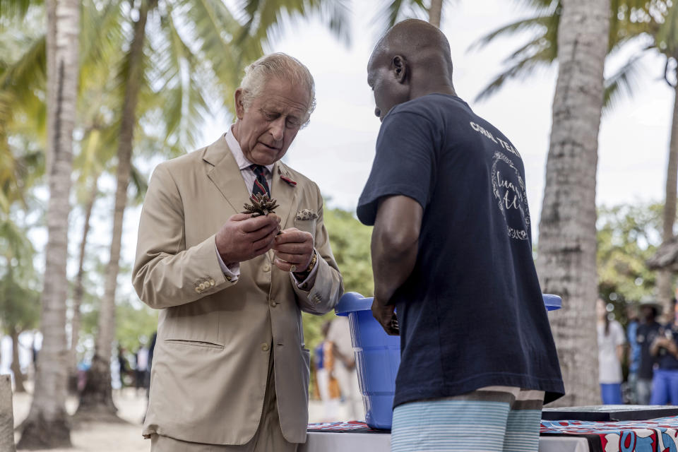 Britain's King Charles III, left, prepares to plant coral on a concrete block to be dropped in the sea, at the coral restoration project during a visit to Kuruwitu Conservation Area in Kilifi, Kenya, Thursday, Nov. 2, 2023. (Luis Tato/Pool Photo via AP)