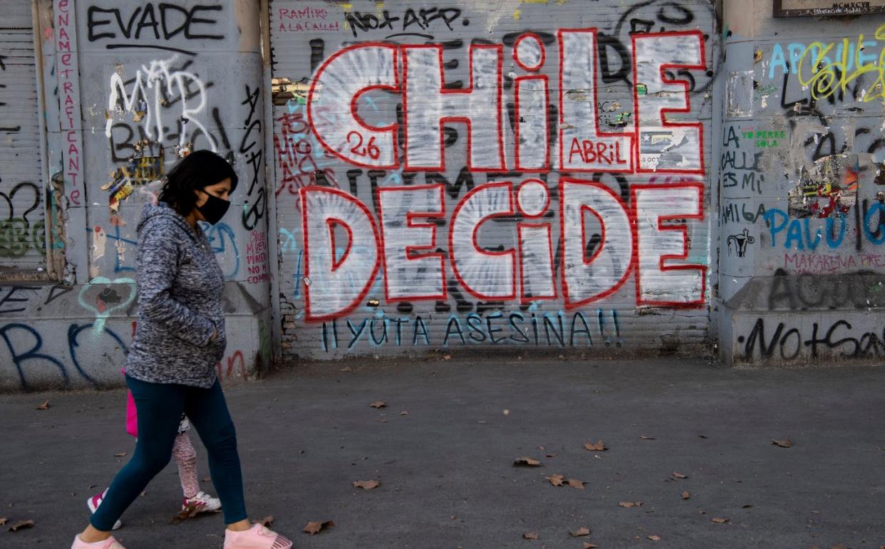 <span class="caption">'Chile Decides' whether to change its military dictatorship-era constitution at a popular referendum on Oct. 25.</span> <span class="attribution"><a class="link " href="https://www.gettyimages.com/detail/news-photo/woman-walks-past-a-graffiti-reading-chile-decides-in-news-photo/1228190415?adppopup=true" rel="nofollow noopener" target="_blank" data-ylk="slk:Martin Bernetti/AFP via Getty Images;elm:context_link;itc:0;sec:content-canvas">Martin Bernetti/AFP via Getty Images</a></span>