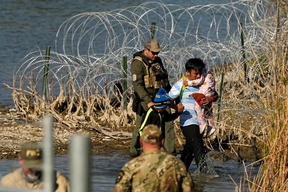 Migrants are taken into custody by officials at the Texas-Mexico border, Wednesday, Jan. 3, 2024, in Eagle Pass, Texas. U.S. House Speaker Mike Johnson is leading about 60 fellow Republicans in Congress on a visit to the Mexican border. Their trip comes as they are demanding hard-line immigration policies in exchange for backing President Joe Biden's emergency wartime funding request for Ukraine. (AP Photo/Eric Gay) ORG XMIT: TXJC111