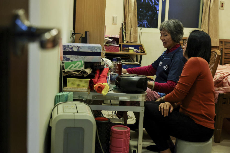 Sixty five-year-old esport player Chiang Yi-Shu, left, practices at home while explaining the game to her daughter Liang Ying-Fang, right in New Taipei city, Taiwan on Friday, Dec. 16, 2022. Chiang is one of the League of Legends players on Hungkung Evergreen Gaming's team, established this summer. The team, whose members range from 62 to 69 years old, was founded by Huang Jianji, the director of the department of Multimedia Game development and application of Hungkuang University. They competed in their first-ever video game tournament Saturday at the university. (AP photo/I-Hwa Cheng)