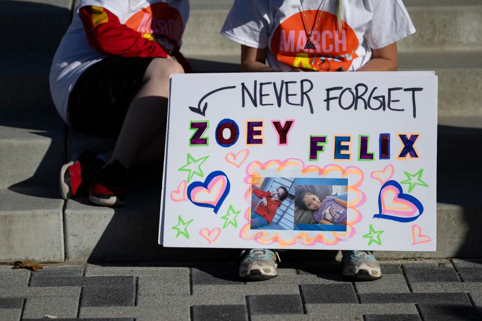 A woman sits with a sign in support of Zoey Felix before participating in Saturday's march from Evergy Plaza to the Kansas Statehouse.
