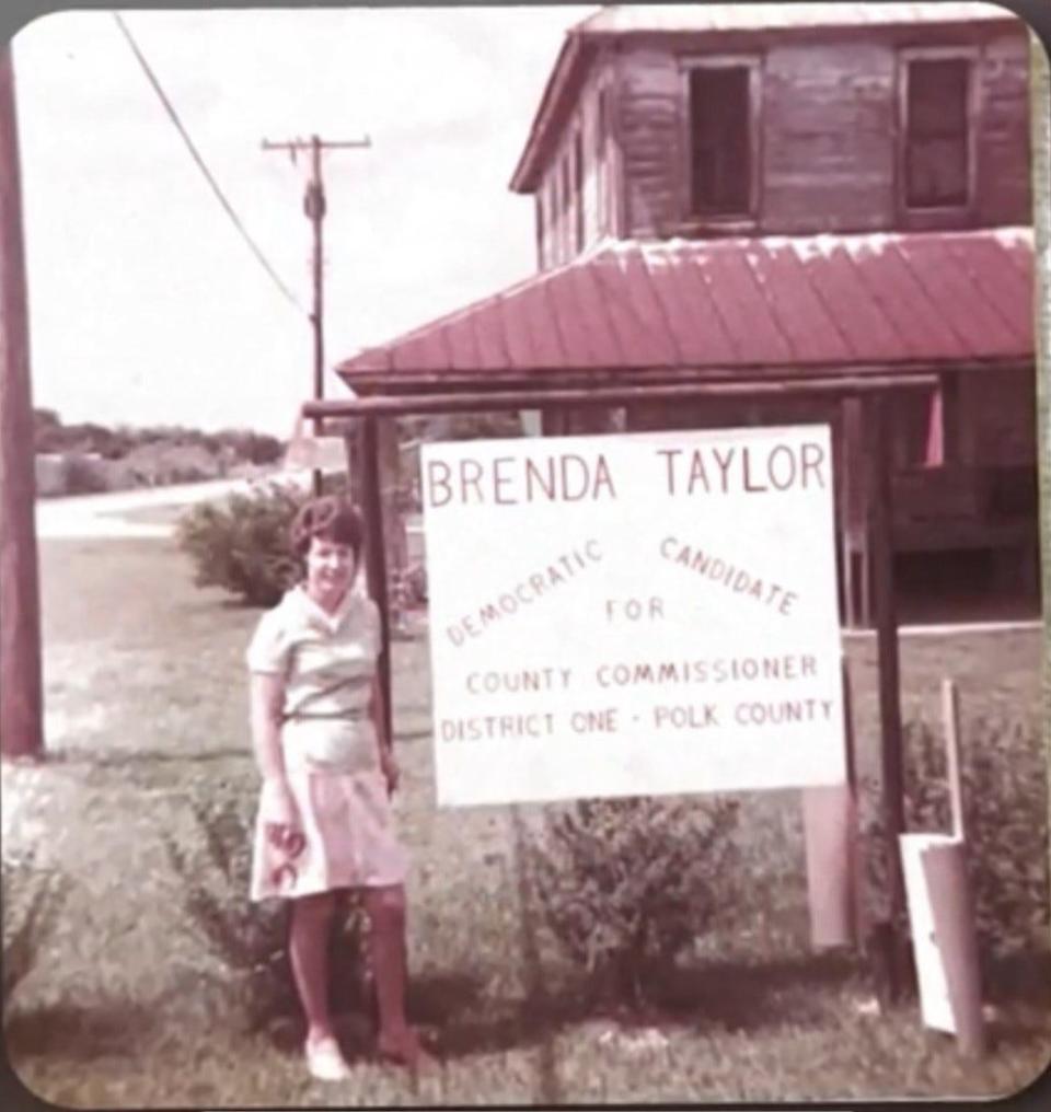 Brenda Taylor, the first woman elected to Polk County Commission, stands next to a campaign poster