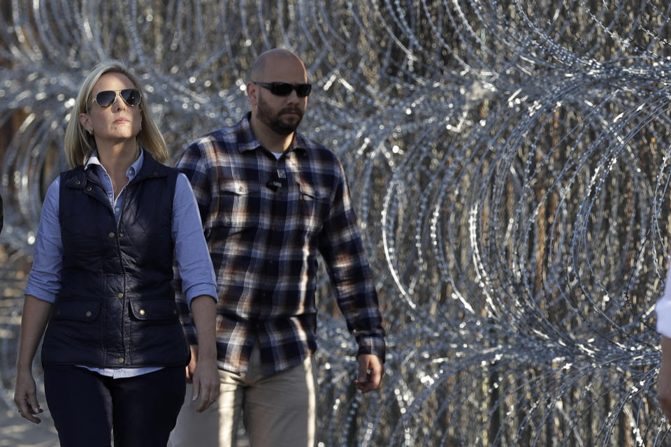 Secretary of Homeland Security Kirstjen Nielsen, left, walks next to a section of the border wall fortified with razor wire separating Tijuana, Mexico, and San Diego, Tuesday, Nov. 20, 2018, in San Diego. Nielsen said Tuesday an appeal will be filed on the decision by a judge to bar the Trump administration from refusing asylum to migrants who cross the southern border illegally. (AP Photo/Gregory Bull)