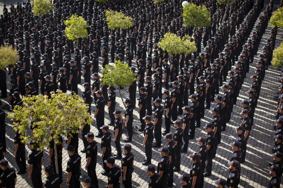 Police cadets attend a graduation ceremony in Madrid, Spain, Tuesday, July 17, 2012. Riot police cordoned off the entrance to a sprawling police facility to prevent demonstrating police officers from disrupting a graduation ceremony for some 1,200 cadets about to enter the police force. The demonstrators were protesting parts of the austerity package, namely the elimination of one of 14 paychecks that most Spanish civil servants get each year. The one being axed comes right before Christmas. (AP Photo/Emilio Morenatti)