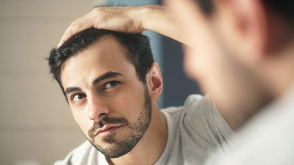 close up of handsome man looking in mirror at home