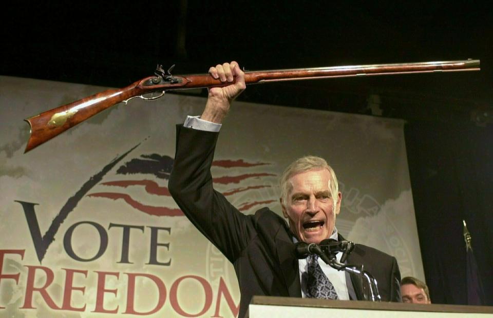 FILE - In this Oct. 21, 2002 file photo, National Rifle Association President Charlton Heston holds up a rifle as he addresses gun owners during a "get-out-the-vote" rally in Manchester, N.H. While American gun-rights are enshrined in the U.S. Constitution - something that doesn't translate to most countries around the world - the NRA's track record of aggressively shaping the debate has nevertheless turned it into the go-to group for other gun-rights activists outside the U.S. (AP Photo/Jim Cole, File)