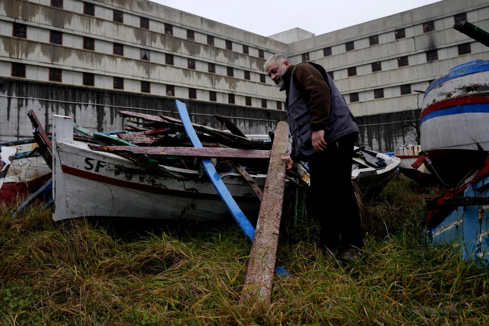 Milan's Opera maximum security prison inmate Andrea Volonghi checks woods of a wrecked migrants' boat stored in the prison facilities, near Milan, northern Italy, Friday, Feb. 9, 2024. Inmates at Opera used the wood of wrecked boats sailed by migrants across the Sicily Channel to craft the musical instruments that the 'Sea Orchestra' used during their debut at La Scala Opera House in Milan on Monday, Feb. 12, 2024. The violins, violas and cellos played by the Orchestra of the Sea in its debut performance Monday at Milan's famed Teatro all Scala carry with them tales of hardship. (AP Photo/Antonio Calanni)