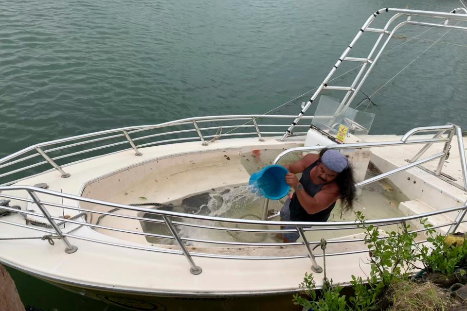 Arnold Balbin bails out water from a commercial parasailing boat moored at the Gregorio D. Perez Marina in Hagatna, Guam, Thursday, May 25, 2023, after Typhoon Mawar went through the area (AP)