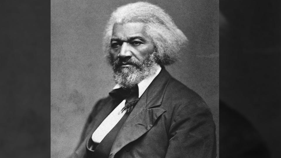 Frederick Douglass in silk-lapelled suit, waistcoat, white, collared shirt and cravat.