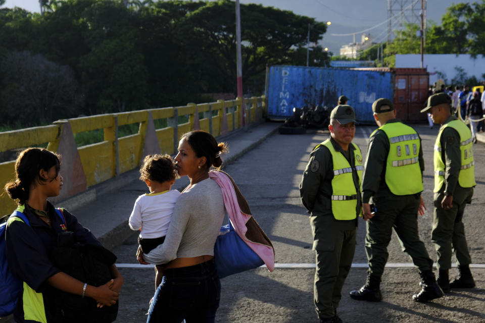 Venezuelans wait to cross the Simon Bolivar international bridge into Cucuta, Colombia, next to Bolivarian National Guard officers, Saturday, June 8, 2019. Venezuela's President Nicolas Maduro ordered the partial re-opening of the border that has been closed since February when he stationed containers on the bridge to block an opposition plan to deliver humanitarian aid into the country. (AP Photo/Ferley Ospina)