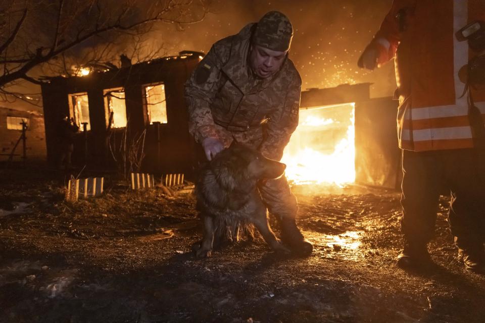 Firefighters rescue a dog as they extinguish a fire following a Russian attack on a residential neighbourhood in Kharkiv, Ukraine, Saturday, Feb. 10, 2024. (AP Photo/Yevhen Titov)