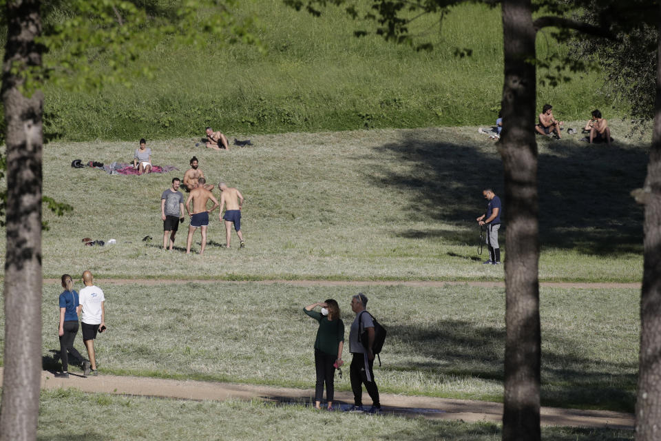 People sunbathe and stroll inside Rome's Villa Pamphili park as it reopened after several weeks of closure, part of nationwide limited easing of some lockdown restrictions, on Monday, May 4, 2020. Italy began stirring again Monday after a two-month coronavirus shutdown, with 4.4 million Italians able to return to work and restrictions on movement eased in the first European country to lock down in a bid to stem COVID-19 infections. (AP Photo/Alessandra Tarantino)