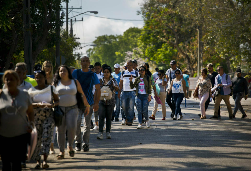 In this April 26, 2019, photo, Cubans wait their turn to enter Panama's embassy to apply for travel visas to Panama, in Havana, Cuba. The surge over the past several months has been propelled in part by loosened traveled restrictions in Central America and deteriorating living conditions in Cuba. (AP Photo/Ramon Espinosa)