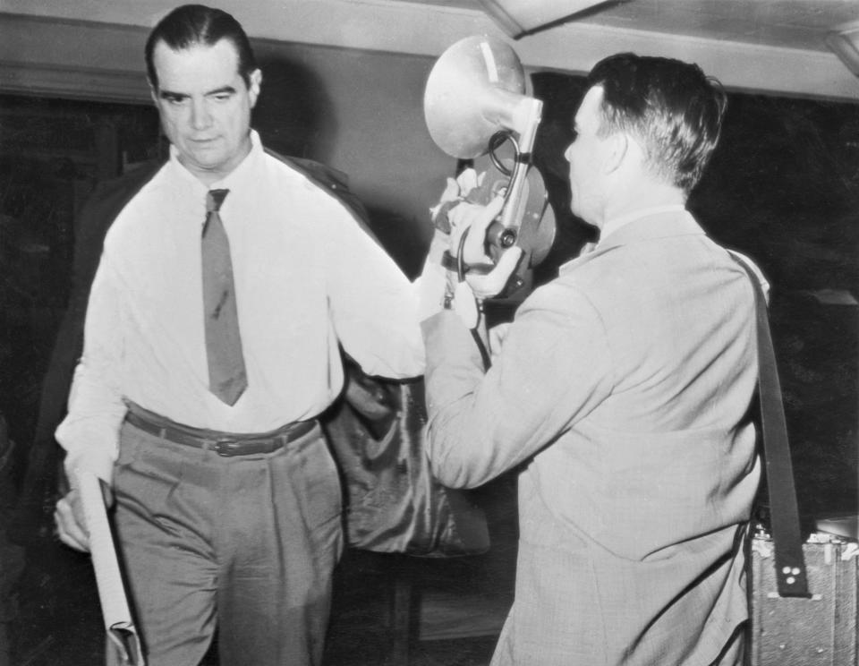 (Original Caption) As he departed from the courtroom where Howard Hughes' left hand is apparently doing TV cameraman Harry Watson's camera no good. Hughes denies that he used the Paul Herrico incident to close down RKO Studios. "That is a ridiculous assumption," says Hughes.