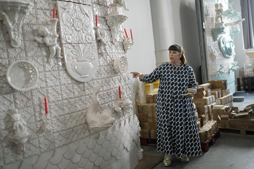 Portuguese artist Joana Vasconcelos points at a full size work model of a section of her 12 meters high and 15 meters wide ceramic wedding cake, at her studio in Lisbon, Friday, Nov. 11, 2022. The Wedding Cake, her most ambitious outdoor project yet, will be erected in the gardens of Waddesdon Manor in southeast England, which hosts weddings. (AP Photo/Armando Franca)